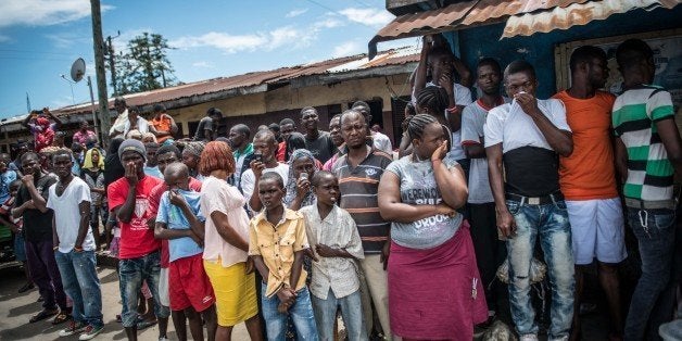 MONROVIA, LIBERIA - OCTOBER 15: People crowd watch Red Cross members as they carry dead body of Mambodou Aliyu (35) died due to the Ebola virus, in Monrovia, Liberia on 15 October, 2014. (Photo by Mohammed Elshamy/Anadolu Agency/Getty Images)