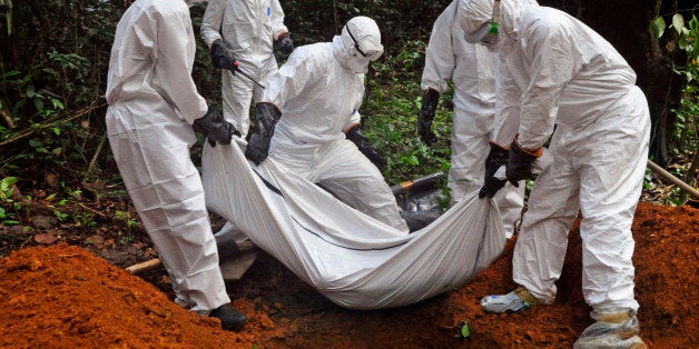 Health workers bury the body of a woman who is suspected of having died of the Ebola virus in Bomi county, on the outskirts of Monrovia, Liberia, Monday, Oct. 20, 2014. Liberian President Ellen Johnson Sirleaf said Ebola has killed more than 2,000 people in her country and has brought it to "a standstill," noting that Liberia and two other badly hit countries were already weakened by years of war. (AP Photo/Abbas Dulleh)