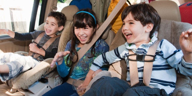 Two brothers (age 4) and sister (age 6) laughing in back seat of mini-van