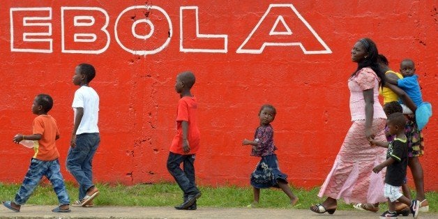 Young women and children walk past a slogan painted on a wall reading 'Ebola' in Monrovia on August 31, 2014. Liberia on August 30, 2014 said it would deny permission for any crew to disembark from ships at the country's four seaports until the Ebola epidemic ravaging west Africa was under control. AFP PHOTO/DOMINIQUE FAGET (Photo credit should read DOMINIQUE FAGET/AFP/Getty Images)