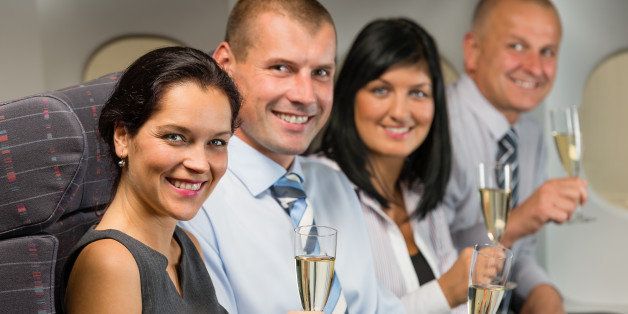 Business people flying airplane drink champagne smiling at camera