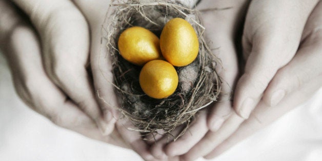 A family of hands holding a nest full of gold eggs.