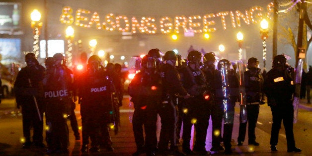 Police gather on the street as protesters react after the announcement of the grand jury decision Monday, Nov. 24, 2014, in Ferguson, Mo. A grand jury has decided not to indict Ferguson police officer Darren Wilson in the death of Michael Brown, the unarmed, black 18-year-old whose fatal shooting sparked sometimes violent protests. (AP Photo/Charlie Riedel)