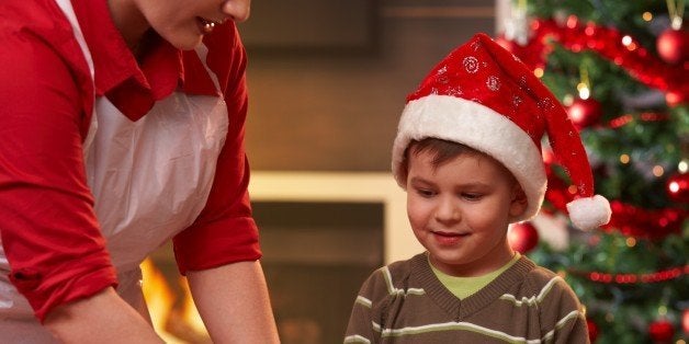 Mother and son making christmas cake, son watching mum's hand, smiling.?