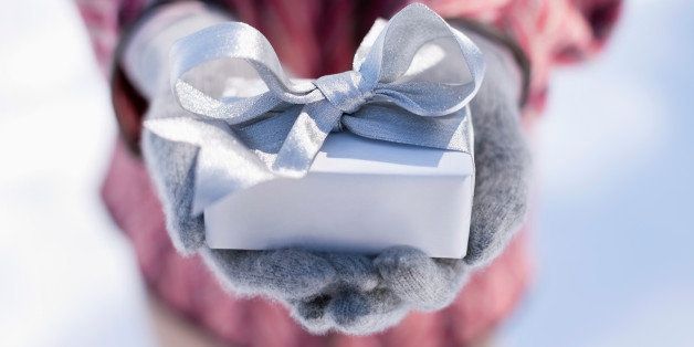 Close up of hands cupping Christmas gift with silver ribbon
