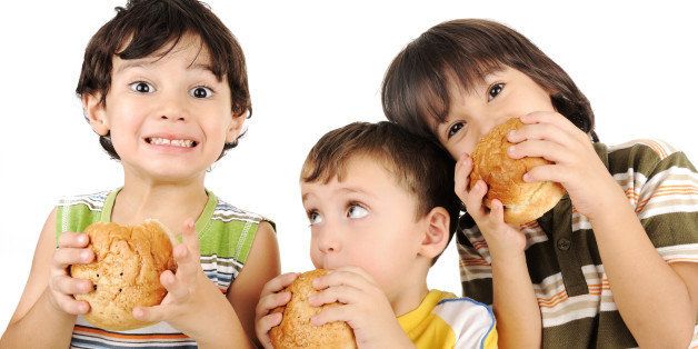 three kids eating burgers