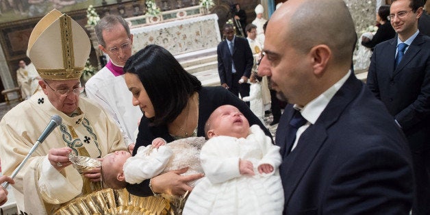 Pope Francis, left, baptizes a baby at the Vatican, Sunday, Jan. 11, 2015. Pope Francis on Sunday baptized 33 babies in the Sistine Chapel as part of an annual tradition, this year repeating an invitation to mothers to nurse their babies if crying out of hunger. For the first time in his pontificate, Francis celebrated Mass with his back to the faithful, according to the rites before the modernizing reforms of the Second Vatican Council in the 1960s. (AP Photo/L'Osservatore Romano, pool)