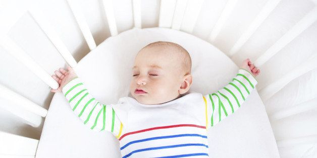 Cute newborn little boy sleeping in a white round crib