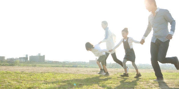 Parents with two kids holding hands and running