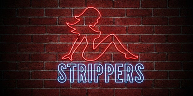 Brigt neon sign of a sexy naked female stripper on a brick wall at night.