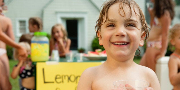 little boy holding glass in front of lemonade