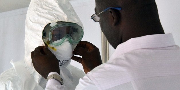 A doctor adjusts the mask of a fellow health worker inside inside a tent in the Ebola treatment unit being preventively set to host potential Ebola patients at the University Hospital of Yopougon, on October 17, 2014. Air Cᅢテᅡᄡte d'Ivoire, the national plane company, announced on October 17 it will resume its flights to Guinea, Liberia and Sierra Leone on Monday. Hysteria over Ebola has reached fever-pitch the world over despite repeated calls for calm.The virus has killed nearly 4,500 people, most of them in Liberia, Sierra Leone and Guinea, and the disease has reared its ugly head further afield in the United States and Spain, sparking post-apocalyptic fears of mass contagion. AFP PHOTO / SIA KAMBOU (Photo credit should read SIA KAMBOU/AFP/Getty Images)