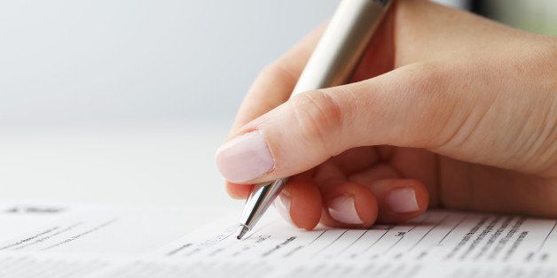 Businesswoman's hand with pen completing personal information on a form