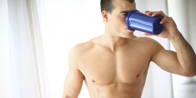 Muscular shirtless guy drinking protein shake after workout.