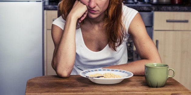 Young woman in her kitchen is dissapointed that she is having cereal for breakfast again