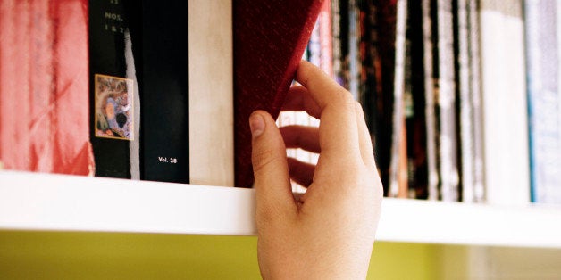 girls hand choosing book from library shelf