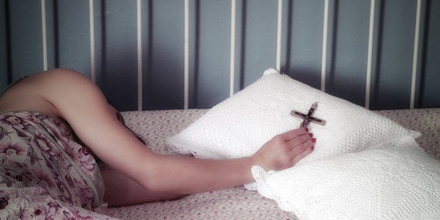 Woman lying on bed holding cross