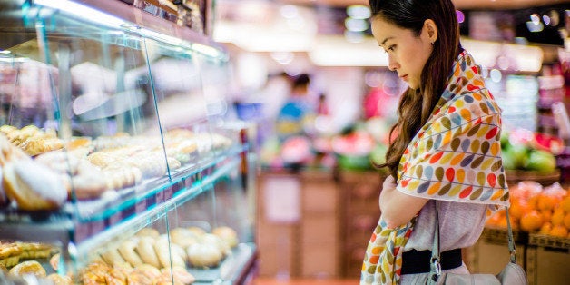 Pretty young lady looking at bakery display in a supermarket.