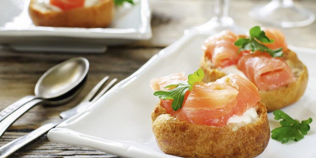 profiteroles with salmon and cream cheese on a dark wood background. tinting. selective focus on parsley on the front profiterole