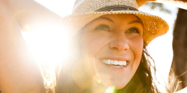 A beautiful woman with a straw hat smiling.