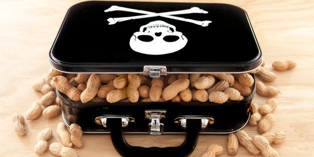 Black lunchbox with skull and crossbones on lid and peanuts overflowing out of container