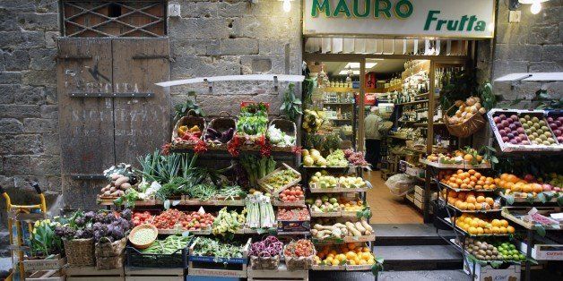 Traditional grocery store selling fruit and vegetable - and a pushcart besides - in a side street of the heart of Florence (Firenze), Tuscany, Italy, Southern Europe