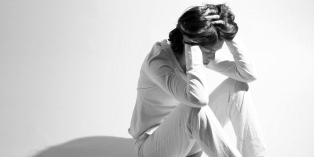 Sad Woman Sitting on Floor and Holding Head in Hands