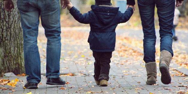 Family with one child walking on pavement street in park.