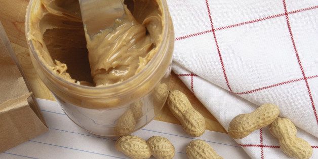 Overhead view of peanut butter on bread with red crayon warning against peanuts which are a dangerous allergen for many children and adults.