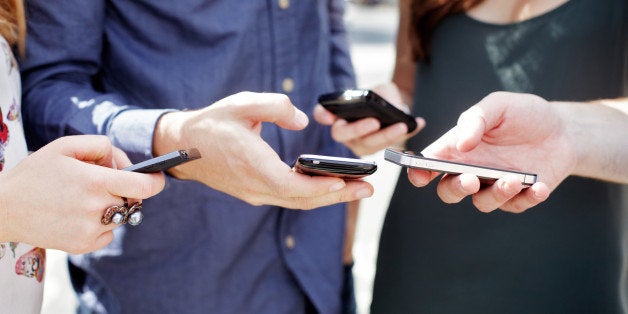 Close up of friends using smart phones.