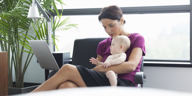 Woman holding baby using laptop