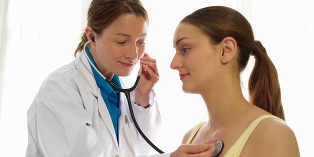 Female doctor using stethoscope on patient.