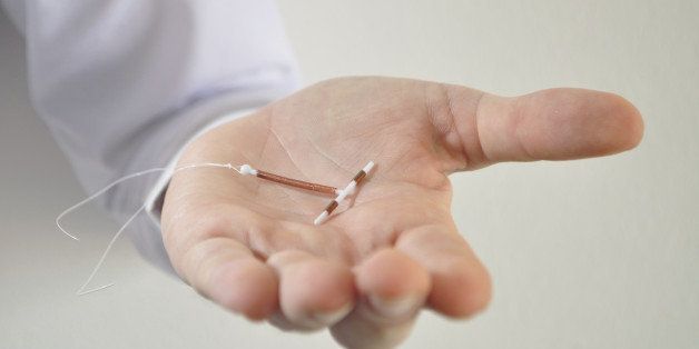 Holding an IUD birth control copper coil device in hand, used for contraception - front view