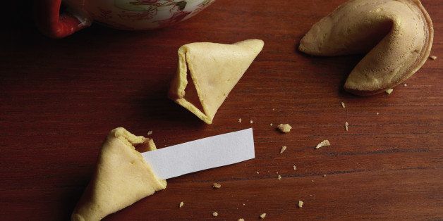 Blank paper in broken fortune cookie on wooden table