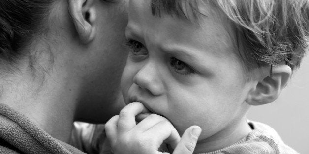 Sad boy, being comforted by his mother. Soft focus black and white.