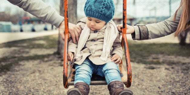 Sad child on a swing, inbetween her divorced parents holding her separatedly .