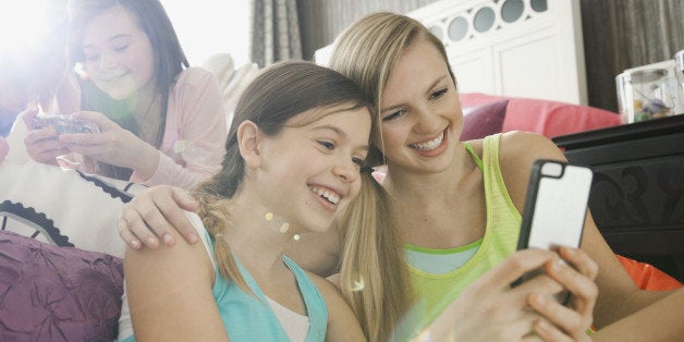 Smiling girls taking self-portrait at slumber party