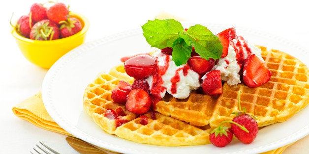 Plate of belgian waffles with fresh strawberries and whipped cream