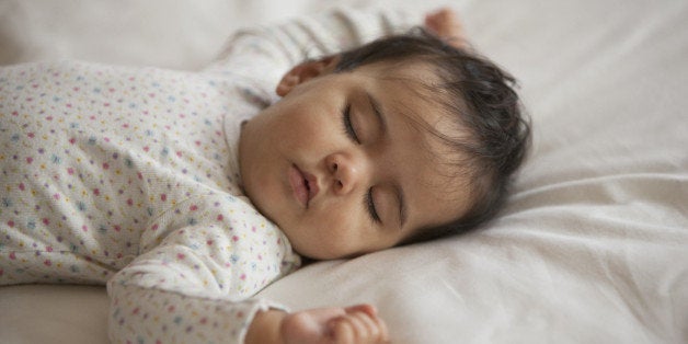 Mixed race baby girl sleeping on bed