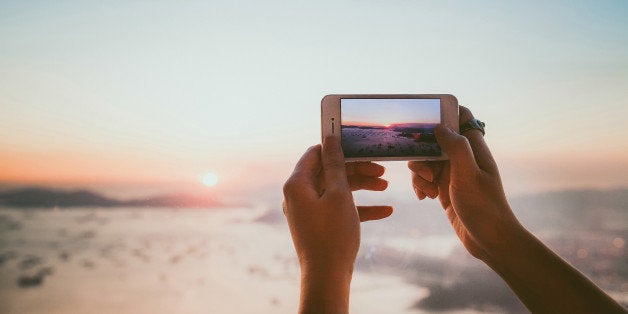 Taking photo of beautiful sunset with smartphone