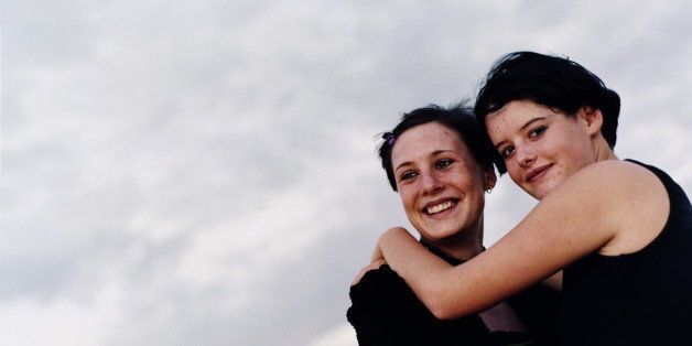 Two teenage girls (15-17) embracing, smiling, portrait