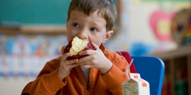 Caucasian boy eating lunch in classroom