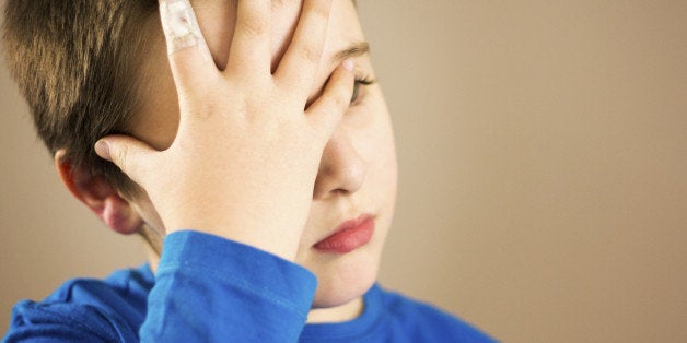 Boy with headache and a bandage on finger.