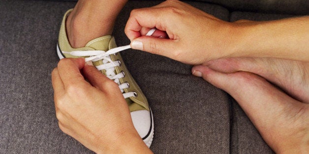 person tying someone's shoes laces