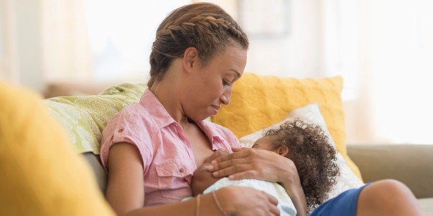 Mixed race mother nursing daughter in living room