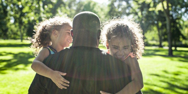 Father playing with twin daughters in park