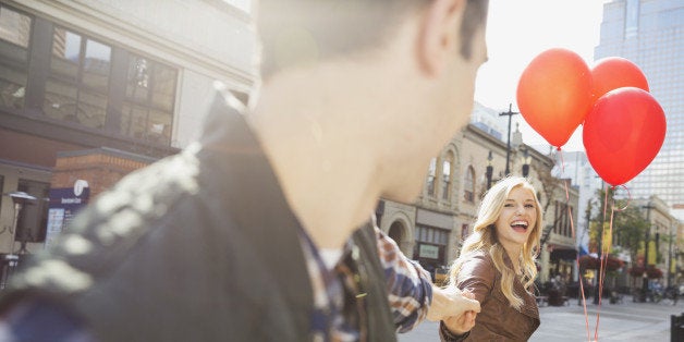 Smiling woman leading man down city street