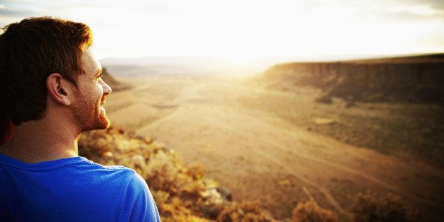 Smiling man looking out over desert canyon at sunset