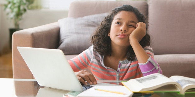 Bored Hispanic girl doing homework on computer