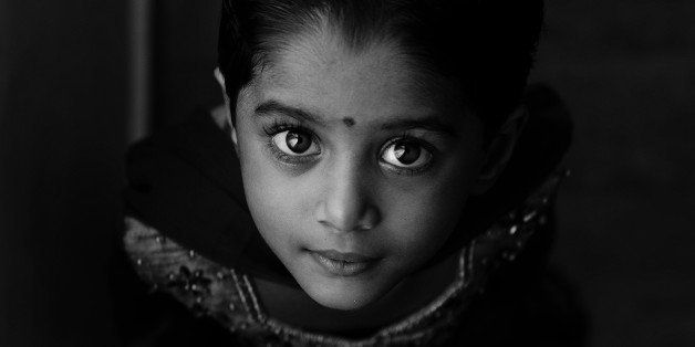 Indian girl Child in traditional dress looking up. Black and white shot. Window lit.